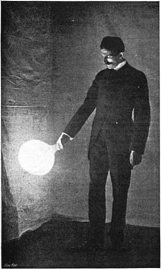 Tesla holding a lightbulb that
            lights up with no wire connection